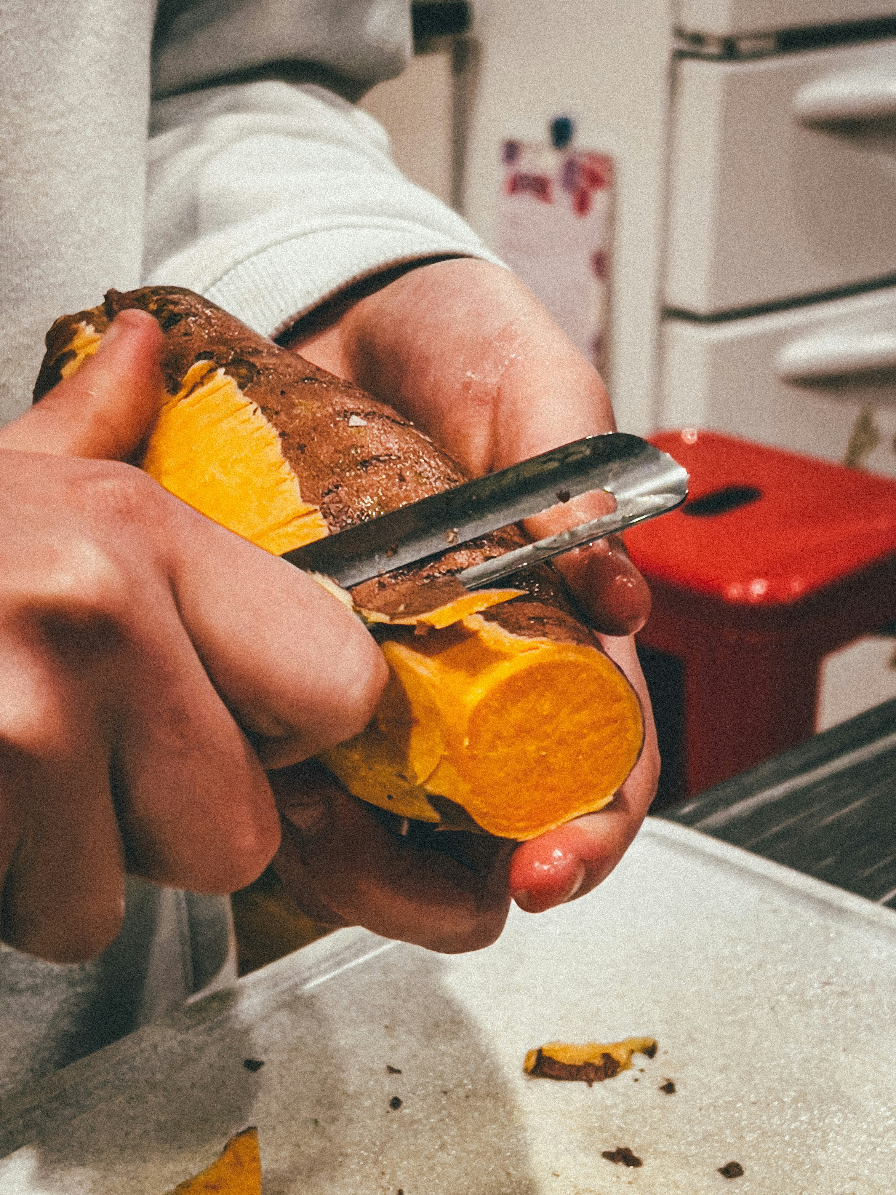 Hands peeling sweet potatoes for Thai curry